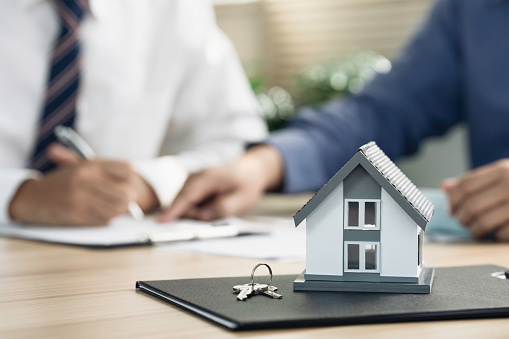 Real estate agents negotiate and helping client about the terms of the home purchase agreement, renting, law, legal and filling contract form on  the table.