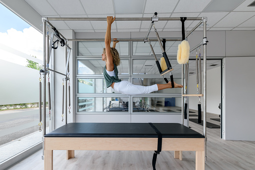 Pilates studio gym: Instructor on trapeze table