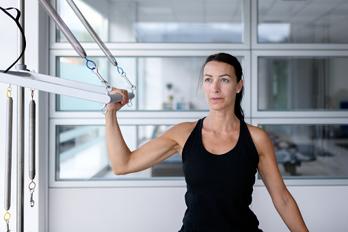 Pilates studio gym: Woman using trapeze table machine