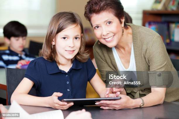 Estudiantes Con El Profesor Ayudando A Elemental Proyecto En Tableta Digital Foto de stock y más banco de imágenes de Estudiante