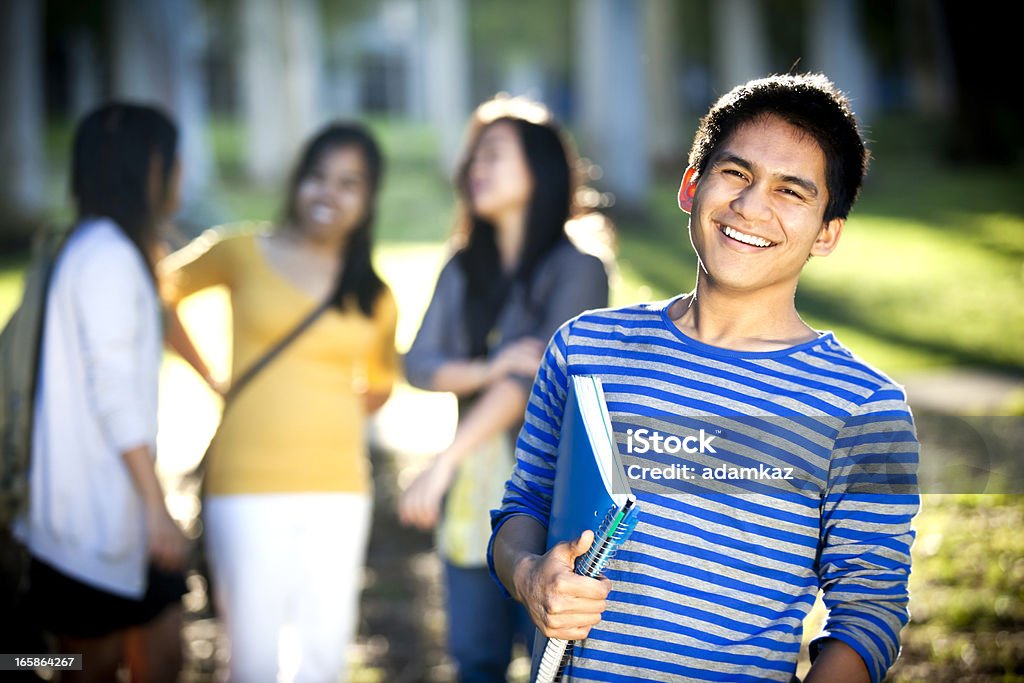 Young Male College Student Young male college student standing with his notepad, 3 college girls in background. 20-29 Years Stock Photo