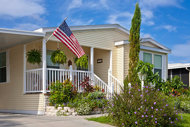 Mobile Home Mobile home with flower garden, front porch, and American flag. Vacation home or retirement home. prefabricated building stock pictures, royalty-free photos & images