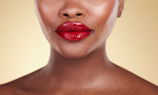 Red, lipstick and woman, beauty and makeup with closeup, skin and shine isolated on studio background. Bold cosmetic product, lips and cosmetology with elegance and glamour with color and glow