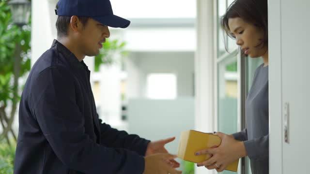 Delivery man send a package box to hand customer at a door home.