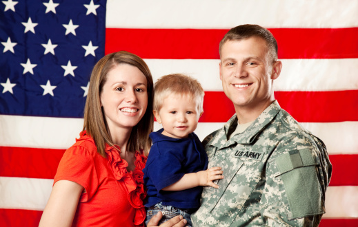 Real American Army family smiling in front of American flag.