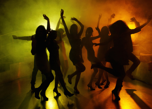 Silhouettes of group of people having fun on dance floor at a night club