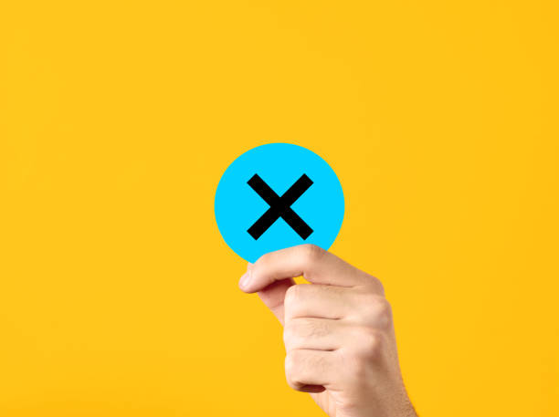 istock Rejection, cancellation, decline, voting no, error, wrong decision or choice concept. Male hand showing a blue circle with cross x symbol on yellow background. 1658693692