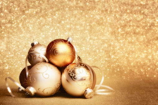 pile of golden christmas baubles on gold glitter background