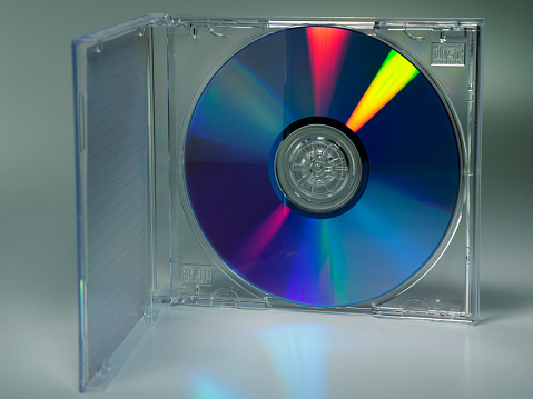 Image of Silver CD on dark background with burst of rainbow colored light across surface