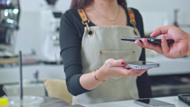 Barista using phone and easy payment in the coffee shop.