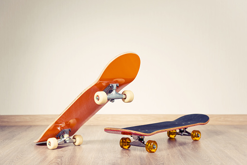 Two skateboards yellow and red on a wooden floor background.