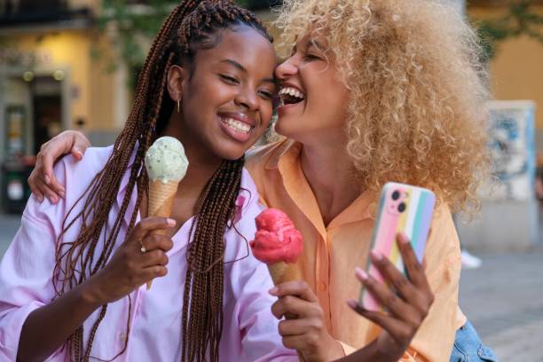 istock Two multiracial happy friends with ice creams laughing in summer. 1658721299