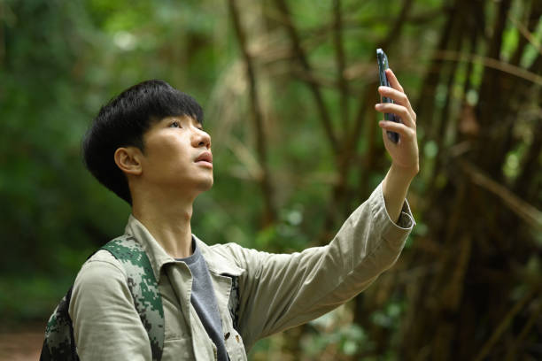 istock Male explorer looking for connection to the internet or using gps navigator app on smartphone in green forest 1658733259