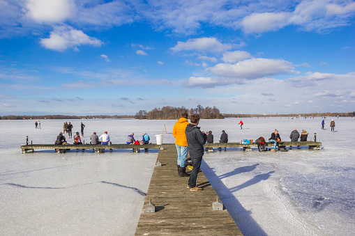 People on the jetty of the frozen lake in Paterswolde, Netherlands