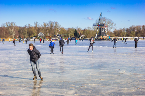 Frozen lake with skaters and windmill in Groningen, Netherlands