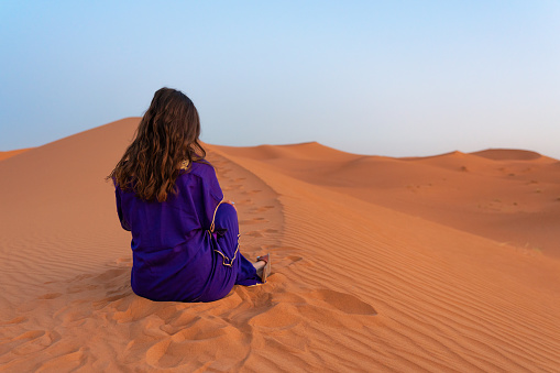 Woman sitting in the desert in traditional dress