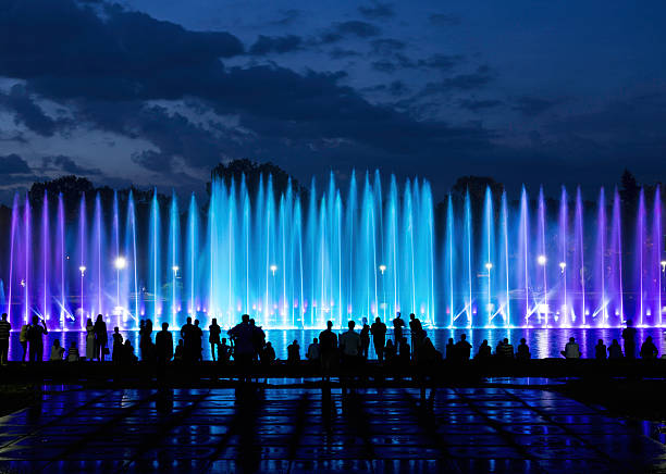 fountain show silhouettes of people at night watching multicolored magic fountain show fountains stock pictures, royalty-free photos & images