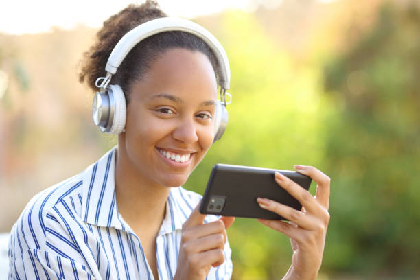 istock Happy black woman with phone and headphone posing 1658749678