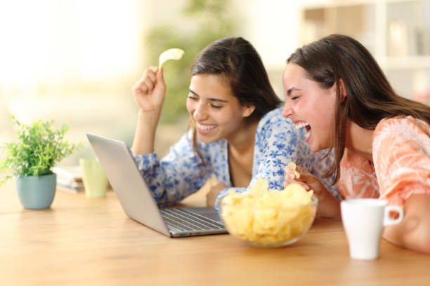 istock Happy roommates watching funny videos eating chips 1658751306