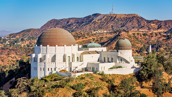 City Of Los Angeles, CA / USA - July 27, 2022: Aerial view of Griffith Observatory against Mount Lee, Hollywood, City Of Los Angeles, California, USA.\n\nGriffith Observatory is an observatory in Los Angeles, California, on the south-facing slope of Mount Hollywood in Griffith Park.\n\nThe Hollywood Sign is an American landmark and cultural icon overlooking Hollywood, Los Angeles, California.