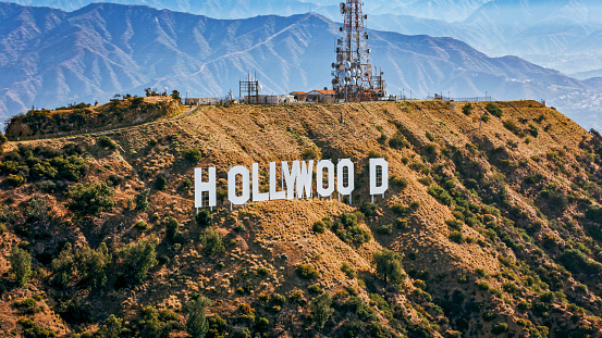 City Of Los Angeles, CA / USA - July 27, 2022: Aerial view of Hollywood sign on Mount Lee against mountain range, Hollywood, City Of Los Angeles, California, USA.\n\nThe Hollywood Sign is an American landmark and cultural icon overlooking Hollywood, Los Angeles, California.