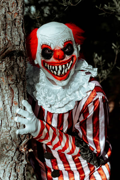 istock mad evil clown pops out of a tree in the woods 1658756742