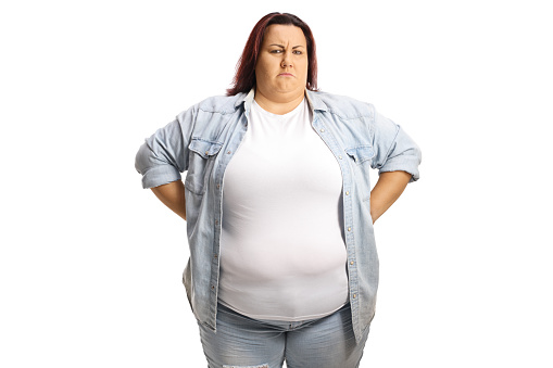 Grumpy overweight woman standing with hands on waist isolated on white background