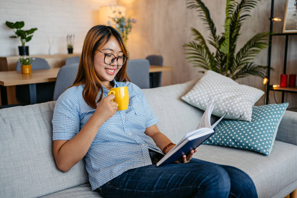 istock Young Woman Reading A Book And Drinking Coffee At Home 1658792106