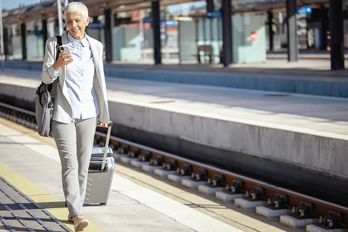 Shot of an elegant senior businesswoman leaves the train station with suitcase