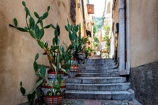 A characteristic narrow alley of Taormina, Sicily, Italy.\nEastsicily, with some typical colored ceramic vases