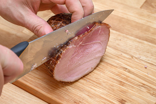 Cut smoked ham into slices, prepare breakfast, closeup
