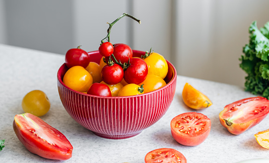 Close-up, a bowl of ripe red and yellow tomatoes on the kitchen table, the concept of harvest and healthy eating.