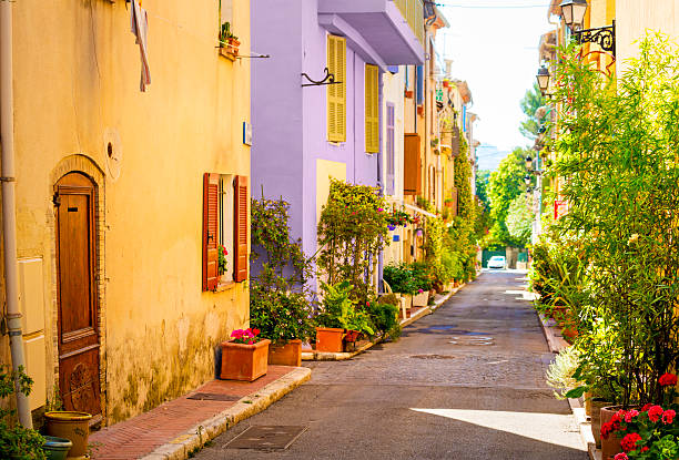 Colorful street in town in Provence, France Narrow street with colorful houses in Mouans-Sartoux (town in Provence-Alpes-Cote d'Azur, France). Shallow depth of field with focus on the nearest door and plants. french riviera stock pictures, royalty-free photos & images