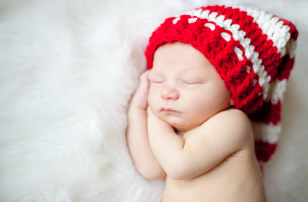 Newborn Baby Sleeping with Red White Striped Hat On. stock photo