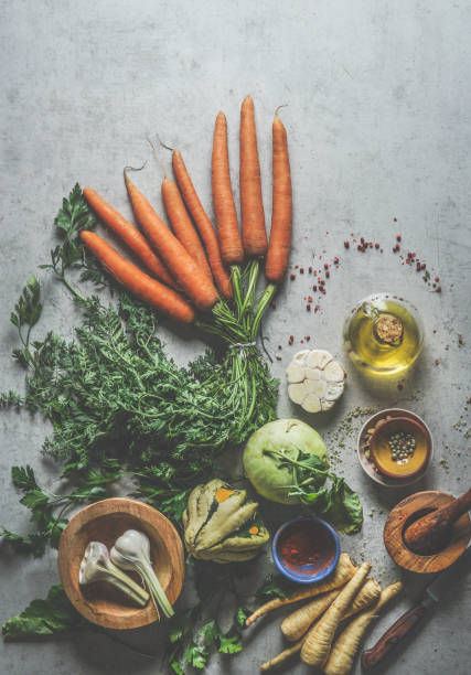 Various healthy vegetarian ingredients: carrots, parsnip, pumpkin, kohlrabi, garlic, spices and kitchen utensils