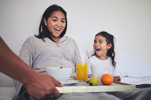 Surprise, breakfast and mother with child in bed relaxing on a weekend morning at their home. Happy, smile and young mom enjoying healthy food for brunch meal with her daughter in their family house.