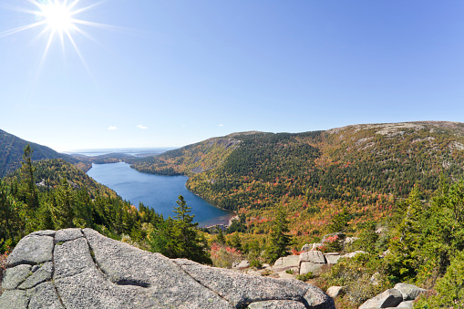 An aerial, fisheye view of Jordan Pond in Autumn from the top of North Bubble, looking east towards the Atlantic Ocean and the Cranberry Isles. Sargent and Penobscot Mountains are in the mid-foreground on the right.