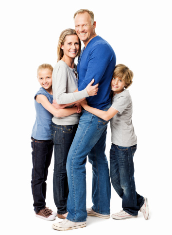 Two children and their parents embrace one another and smile at the camera. Vertical shot.