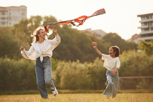 Playing with kite. Woman with her little daughter are on the summer field together.