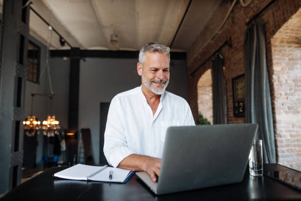 istock Senior businessman working in modern bright office. Mature entrepreneur using laptop for work 1658865328