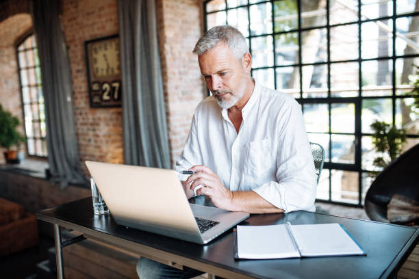 istock Senior businessman working in modern bright office. Mature entrepreneur using laptop for work 1658867459