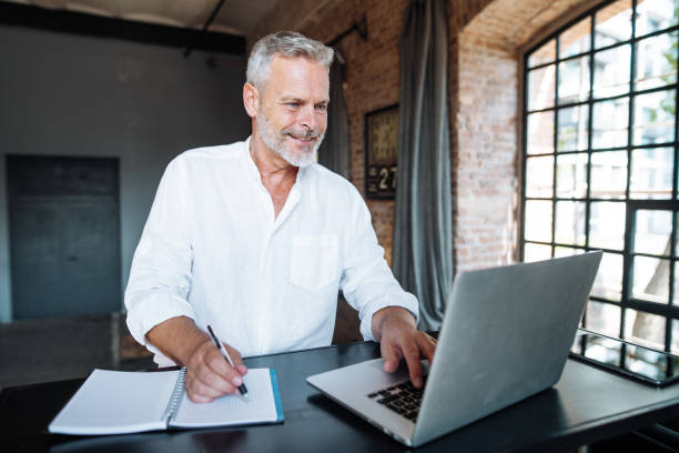 istock Senior businessman working in modern bright office. Mature entrepreneur using laptop for work 1658867995