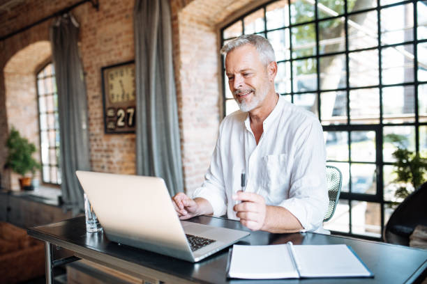 istock Senior businessman working in modern bright office. Mature entrepreneur using laptop for work 1658868554