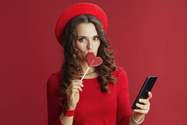 istock woman on background with heart shaped candy using phone 1658875638