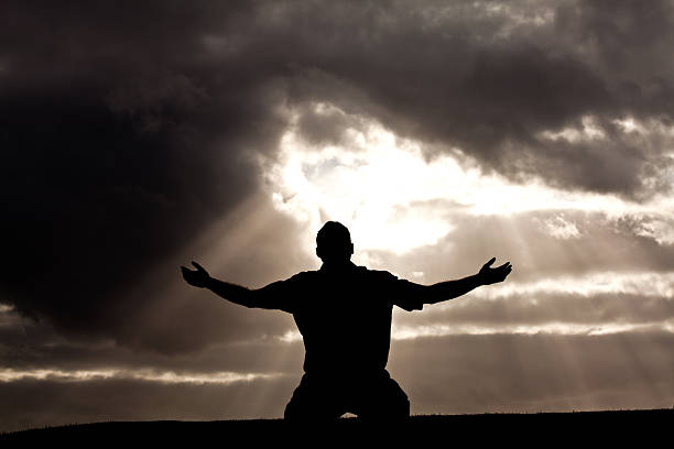 Silhouette of Unrecognizable Man in Worship Silhouette stock photo