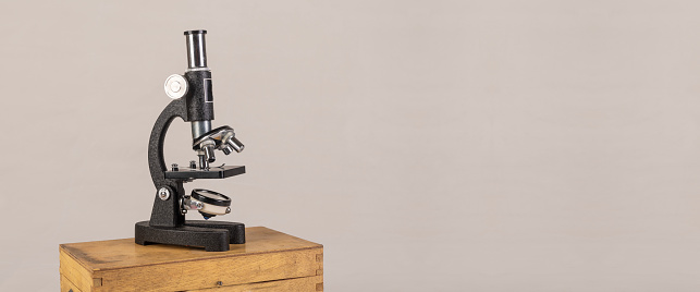 Microscope on wood box clear banner background with copy space.