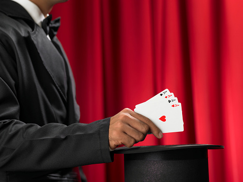 Magician make performance with card deck and top-hat