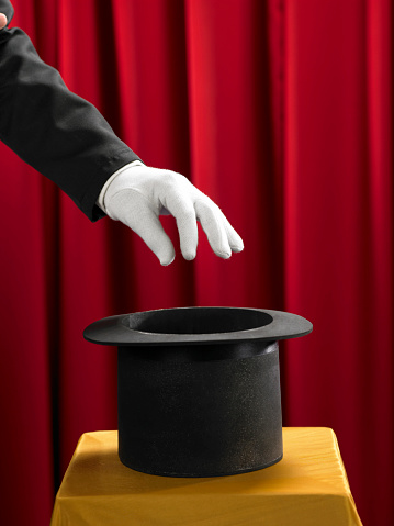 Hands of the magician with top hat on stage.