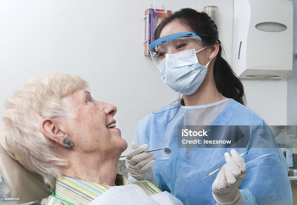 Dentist Appointment - Hygienist and Senior Patient A female dental hygienist smiles and talks with an elderly female patient as she prepares to work on her teeth.   Dentist Stock Photo