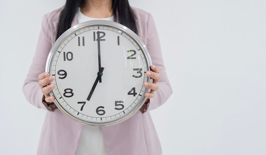 Cropped image of Asian business woman wearing business clothes and holding big clock over white background. Business times concept